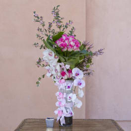 Tall pink and white orchid arrangement in a glass vase