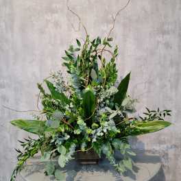 Tall green floral arrangement in a dark rectangular vase