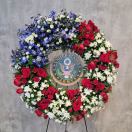 Large floral wreath with red roses, white daisies, and blue flowers around a U.S. Army emblem