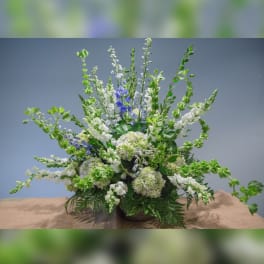 Large floral arrangement with white and blue flowers in a low container