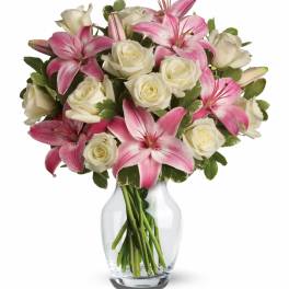 Arrangement of pink lilies and white roses in a clear glass vase