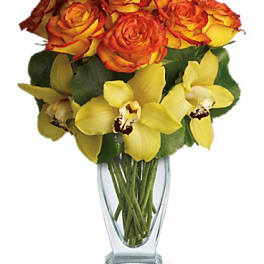 Orange roses and yellow orchids in a clear glass vase