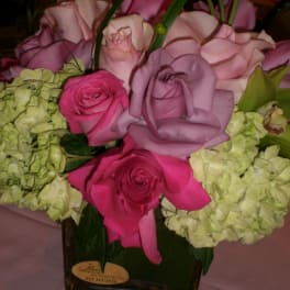 Pink and lavender roses with pale green hydrangeas in a square vase