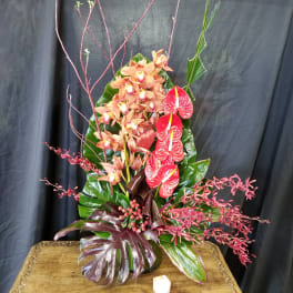 Tall tropical arrangement with orchids and red anthuriums in a vase