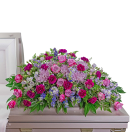 Pink and lavender flower casket spray arranged on a light pink casket
