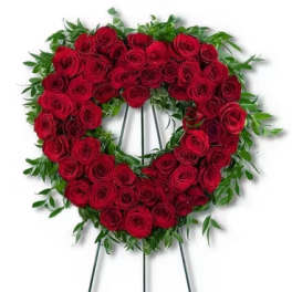 Heart-shaped wreath of red roses on a metal easel stand