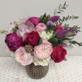 Bouquet of pink, purple, and red flowers in a textured vase