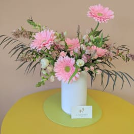 Pink gerbera daisies in a white vase with mixed pastel flowers