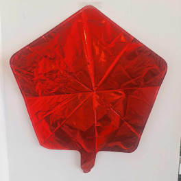 Red star-shaped foil balloon on a white wall