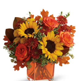 Bouquet of sunflowers and orange roses in a square vase