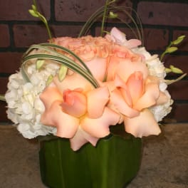 Peach roses and white hydrangeas in a green vase