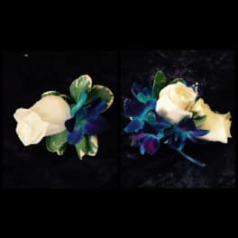 Two white rose boutonnieres with blue-purple orchids on a dark background
