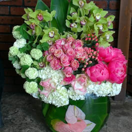 Bouquet of pink roses, green orchids, and white hydrangeas in a green vase
