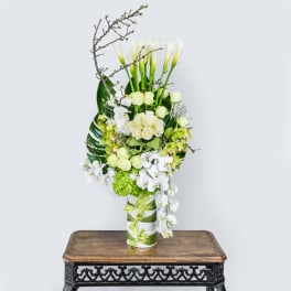 Tall white and green floral arrangement in a ribbon-wrapped vase