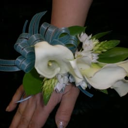 White calla lily corsage with blue ribbon and green leaves