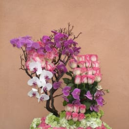 Pink roses and purple orchids arranged on a floral base