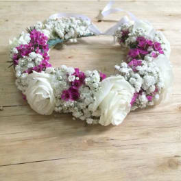 White and magenta floral wreath with ribbon ties on a wooden surface