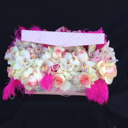 Pink and white floral arrangement in a decorated box with feathers