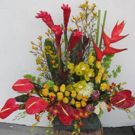 Tall tropical flower arrangement with red anthuriums, yellow orchids, and red heliconia