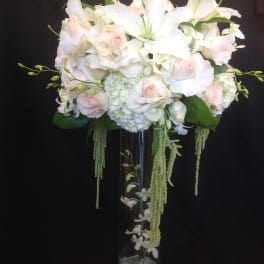 White lilies and pale pink roses in a tall glass vase
