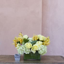 Yellow roses and pale hydrangeas arranged in a green vase