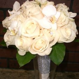 Cream rose bouquet with white orchids in a clear vase