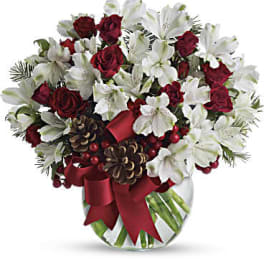 Red roses and white lilies in a glass vase with a red ribbon
