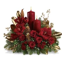 Red roses with candles and gold accents in a holiday centerpiece