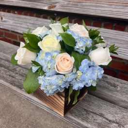 Bouquet of white roses and blue hydrangeas in a wooden box
