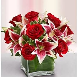 Red roses and pink lilies in a square glass vase