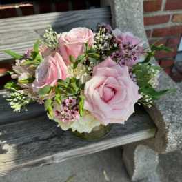 Pink roses arranged in a low glass vase with small filler flowers
