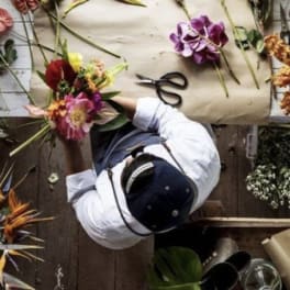Florist arranging colorful flowers on a worktable with scissors and paper