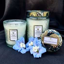 Three lavender-scented candles with blue flowers in front
