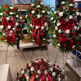 Three standing floral wreaths with red and white flowers and red ribbons