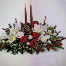 Holiday centerpiece with red and white flowers, pinecones, and two tall candles