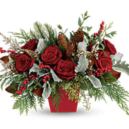Red roses in a red container with pinecones and berries