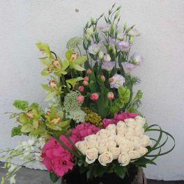 Tall floral arrangement with cream roses, pink hydrangeas, and green orchids