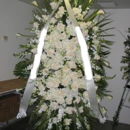 Large white funeral spray with roses and lilies on a standing easel
