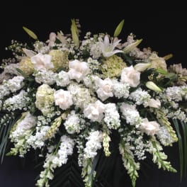 Large white funeral spray with lilies, roses, and clustered white blooms