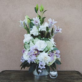 Tall white and lavender floral arrangement in a silver vase