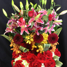 Tall bouquet of red roses and pink lilies with mixed blooms in a black container