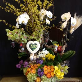Large floral arrangement with orchids, roses, and tulips in a decorative base