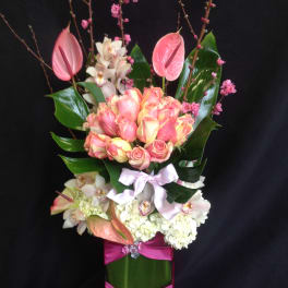 Tall bouquet of pink and white flowers with a ribbon-wrapped vase