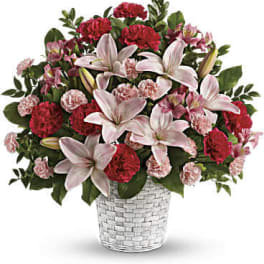 Pink lilies and red carnations in a woven glass vase