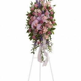 Tall standing floral spray with pink roses and purple accents on an easel