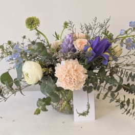 Mixed bouquet in a glass vase with blue, peach, and white flowers