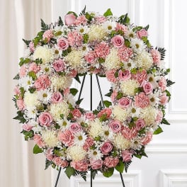 Pink and white floral wreath on a black stand