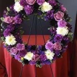 Purple and white floral wreath on a stand