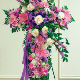 Standing floral cross with pink and white flowers and a purple ribbon