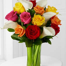 Bouquet of multicolored roses and white calla lilies in a glass vase